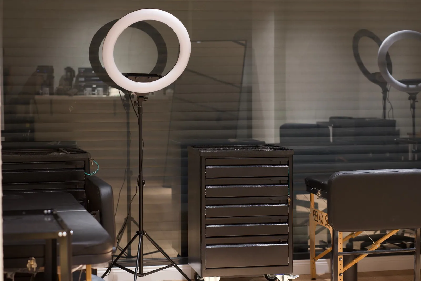 Cam bölme ardında ring ışık ve çekmeceli istasyon — NEXA Atelier iç mekan