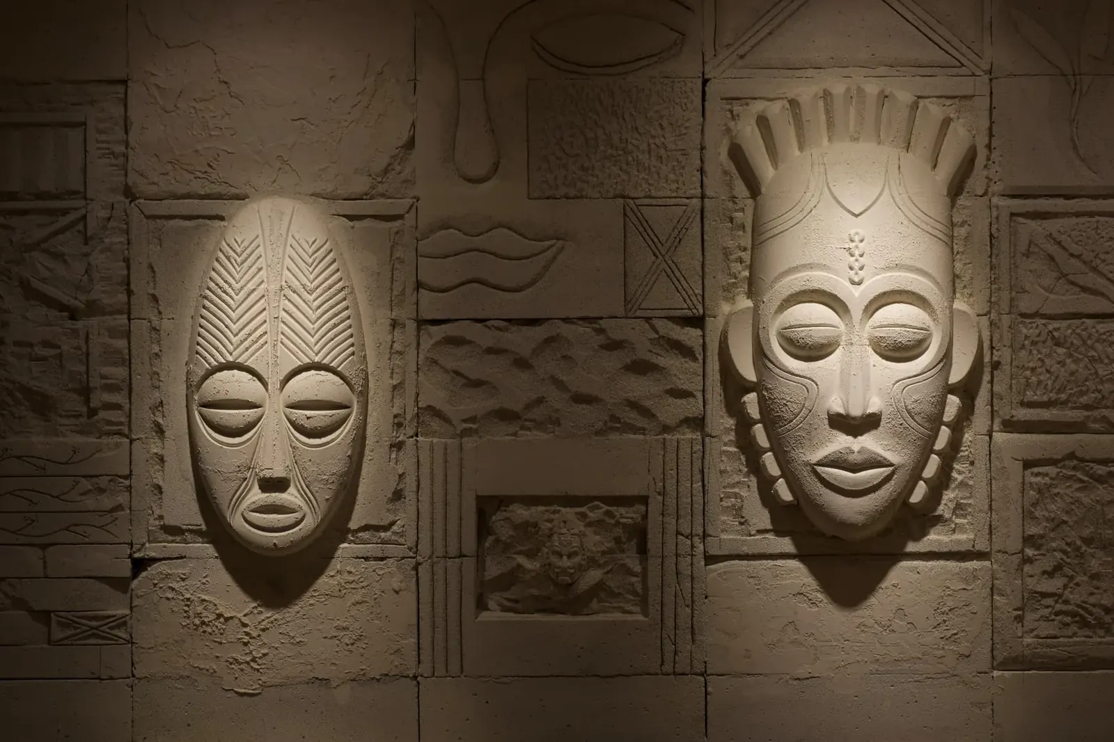 NEXA Atelier duvarında el işçiliği taş kabartma maske ve geometrik rölyef motifler
